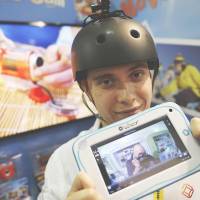 Toy story: At a London toy fair, Alexandra Delage from Lexibook holds a tablet connected wirelessly to a mini camera that is attached to his helmet. Can traditional toys fend off the tablet?