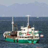 Hove to: The freighter Shinriki Maru drifts Friday off Yura, Wakayama Prefecture, after colliding with a pair of trawlers in the morning, one of which floats capsized. Freighter, trawlers collide, leaving two fishermen dead