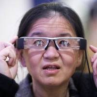 Visionary?: An attendee tries the Epson Moverio BT-200 smart glasses at the International CES in Las Vegas on Tuesday. The glasses project two identical images onto the lens-based screens, generating a semi-transparent picture within one’s field of vision. Few 'wearables' make fashion sense