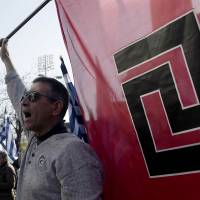 Dark days: Supporters of the Greek ultranationalist Golden Dawn party shout slogans outside a courthouse in Athens on Saturday. Another Golden Dawn MP placed behind bars