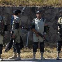 A Pakistani police officer scans an area as paramilitary troops stand alert outside a court in Islamabad on Thursday. Musharraf suffers 'heart problem' on way to treason hearing