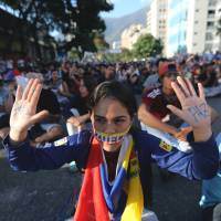 A young demonstrator taking part in a rally in Caracas on Sunday shows the Spanish word for peace written on her hands. Students lead Venezuelan protests