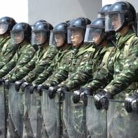 Ready to react: Thai soldiers stand guard during a Thai farming protest in Bangkok on Monday. First key protest leader arrested in Thailand