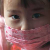 A girl wearing a face mask rides a school bus to the Emporium Kindergarten in the city of Koriyama, west of the crippled Fukushima No. 1 nuclear power station in Fukushima Prefecture, on Feb. 28. Life indoors exacts toll on Koriyama children