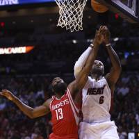 That’s mine: Rockets guard James Harden (left) and the Heat’s LeBron James vie for a rebound on Sunday in Miami. Heat get back on track with victory