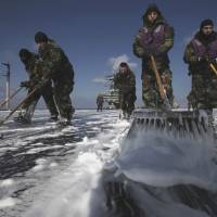 Decontamination time: U.S. Navy crews mop up the flight deck to remove radioactive substances from USS Ronald Reagan on March 23, 2011, off the coast of Tohoku, after the aircraft carrier's forces spent 10 days helping with rescue and aid missions in the wake of the 3/11 earthquake and tsunami. Stakes high as ailing U.S. Navy sailors take on Tepco over Fukushima fallout
