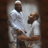 Islamist defendants accused of terrorism-related charges look through their cage bars in a Nasr City cell trial with other defendants at a courtroom in Cairo on Wednesday. The trial was adjourned to Monday. Egypt prosecutor orders new mass trials of 919