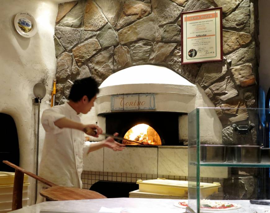 Pizzeria Tonino Eating Italian: A pizzaiolo works the furnace at Pizzeria Tonino. | ROBBIE SWINNERTON