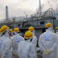 Members of the International Atomic Energy Agency inspect the crippled Fukushima No. 1 nuclear power plant during their review mission on the plant’s decommissioning process on Nov. 27. Critics hit nuke power justification