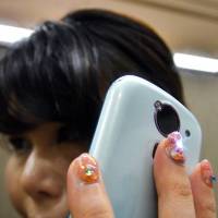 Toymaker Takara Tomy Arts’ LumiDecoNail stick-on fingernails with LED light and antenna are seen Wednesday at its photo exhibition in Tokyo. LED nails light up when calling