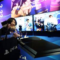A customer holds a bag with a new PlayStation 4 video game console inside after purchasing it at Sony's showroom in Tokyo on Feb. 22. Sony PS4 sales top 7 million mark