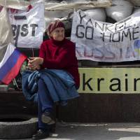 A pro-Russia activist holds the country’s flag outside a regional government building occupied by protesters in Donetsk, eastern Ukraine, on Saturday. A collection of contradictions, east Ukraine's pro-Russian militants dig in