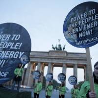 Members of environmental activist group Greenpeace pose with placards that read Power to the people! Clean energy now in front of the Brandenburg Gate in Berlin on Sunday. The U.N. Intergovernmental Panel on Climate Change (IPCC) presented its third and final chapter of a mammoth overview on climate change the same day. U.N. climate goal feasible but energy reform vital: IPCC