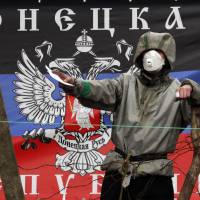 A pro-Russian militiaman holds a piece of paper as he guards a barricade in front of the flag of the so-called Donetsk Republic outside a regional police building in Ukrainian city of Slavyansk on Monday. Ukraine’s latest ultimatum to pro-Kremlin militias who have seized buildings across a swath of the separatist east expired the same day without any sign that the gunmen are ready to give in. Ukraine seeks U.N. peacekeepers for restive east as eviction deadline passes