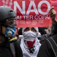 A masked protester holds a banner that reads in Portuguese, “There won’t be a Cup,” in reference to FIFA’s 2014 World Cup, during a demonstration against money spent on the preparations for the international soccer tournament, in Sao Paulo on Saturday. Soccer's crown jewel can't hide Brazil tensions