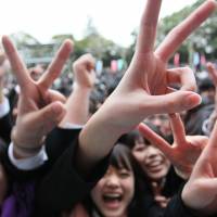 Vocational school students flash the victory sign at the beginning of a job-hunting rally in Tokyo in 2010. Mobile-fixated girls easy prey for photo-snapping pervs