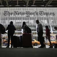 People wait for cabs across the street from The New York Times building in New York on Wednesday. The Times announced last week that Executive Editor Jill Abramson was being replaced by Managing Editor Dean Baquet after 2½ years on the job. Women at top 'more likely to be fired'