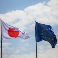 The Hinomaru flies beside the European Union flag as Prime Minister Shinzo Abe and German Chancellor Angela Merkel held a news conference at the Chancellery in Berlin last Wednesday. EU demands human rights clause linked to economic partnership agreement with Japan