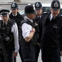 British police officers gather outside Portcullis House after the arrival of Pfizer CEO Ian Read for a committee hearing in London on Tuesday. Lawmakers to press Pfizer chief for job guarantees after AstraZeneca takeover