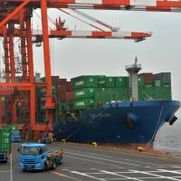 Shipping containers are loaded onto a freighter at a pier in Tokyo on Wednesday. Trade deficit shrinks as energy imports fall
