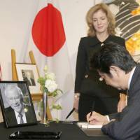Prime Minister Shinzo Abe signs the condolence book for former Ambassador Howard Baker at the U.S. Embassy in Tokyo on Monday as current Ambassador Caroline Kennedy looks on. Abe signs condolence book for former envoy Baker
