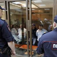 Defendants in the murder trial of Russian journalist and human rights activist Anna Politkovskaya sit inside a glass-walled cage, guarded by policemen, during a court hearing in Moscow on Monday. Five sentenced for slaying of Russian journalist, but mastermind remains unknown