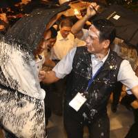Security personnel protect Zhang Zhijun (center, white shirt), director of China’s Taiwan Affairs Office, with bullet-proof suitcases in Taiwan as anti-China protesters attempt to douse him with white paint in Kaohsiung on Friday. Taiwanese leave China envoy's historic convoy splattered in protest paint