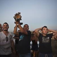 An Israeli man holds up part of a rocket that was fired toward Israel from the Gaza Strip as he watches rocket-fire together with others from a hill near Sderot on Sunday. Thousands fled their homes in a Gaza town the same day after Israel warned them to leave ahead of threatened attacks on rocket-launching sites, on the sixth day of an offensive that Palestinian officials said has killed at least 160 people. Militants in the Hamas-ruled Gaza Strip kept up rockets salvoes deep into the Jewish state and the worst bout of Israel-Palestinian bloodshed in two years showed no signs of abating. Gazans flee the north fearing a major Israeli onslaught