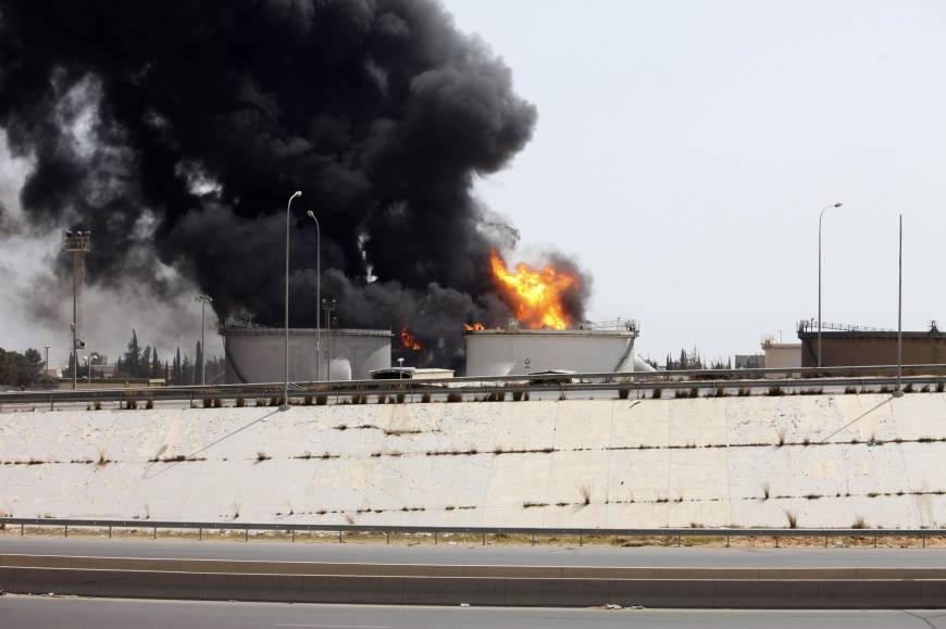 A fuel depot burns Monday near the airport road in Tripoli. Libyan forces on Tuesday battled Islamist militants with rockets and warplanes for control of an army base in Benghazi after at least 30 people were killed in overnight fighting. A rocket hit the fuel depot two days ago. Libya militias wage heavy battle as Tripoli inferno rages