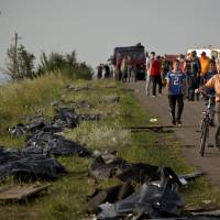 Bodies of victims are placed in plastic sacks by the side of the road at the crash site of Malaysia Airlines Flight 17 near the village of Hrabove, eastern Ukraine, on Saturday. Carriers symbolize nations' hopes or reflect countries' shame