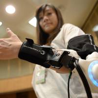 During a news conference in Kawasaki on June 18, an official from the Kawasaki Municipal Government conducts a demonstration using a powered exoskeleton developed by robot-suit venture Cyberdyne. Sci-fi scenarios now a reality in medical world