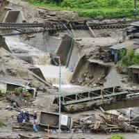A work crew starts the cleanup process after a flash flood tore through Nagiso, Nagano Prefecture, on Wednesday, destroying at least two houses and ripping away bridges. Typhoon leaves seven dead as it heads toward Tokyo