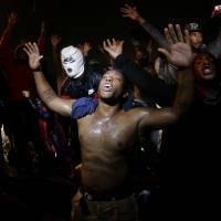 People defy a curfew Sunday to protest the death of teenager Michael Brown at the hands of local police in Ferguson, Missouri, last Saturday. Brown’s shooting in the middle of a street following a suspected robbery of a box of cigars from a nearby market has sparked a week of protests, riots and looting in the St. Louis suburb. Ferguson police fail to learn from past incidents of racial unrest