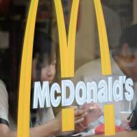 Customers sit behind the logo on a window of a McDonald's restaurant in Tokyo last week. Fast-food follies have media in a frenzy