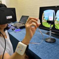 A journalist tries out a new device that uses tactile feedback 3-D technology at a press preview in Tsukuba, Ibaraki Prefecture, on Monday. Japanese firm showcases 'touchable' 3-D technology
