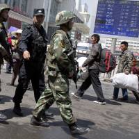 Paramilitary policemen carrying guns march past the site of an explosion outside Urumqi South Railway Station in Urumqi, the capital of China's western Xinjiang region, in May. Use of deadly force up amid Uighur crackdown