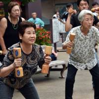 People work out with wooden dumbbells outside a temple in Tokyo on Monday to celebrate Respect for the Elderly Day. Japan's population of centenarians continues to grow