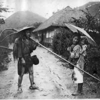 Rein it in: A man looks on at a young woman and her child during a rainstorm, in a photo shot sometime during the 1910s. 'Nihon danshi’ continue to look on as stockings get stronger