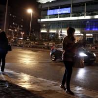 A woman walks on a sidewalk Thursday in front of the headquarters of the New Democracy party in Athens. Greek police foiled a planned weekend bomb attack by a far-left militant group against the headquarters this weekend, when the party plans to celebrate its 40th anniversary. Greek police foil far-left militant bomb plot