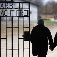 A couple walk past the Arbeit Macht Frei (Work Sets You Free) sign, located at the main gate of the Sachsenhausen Nazi concentration camp in Oranienburg, Germany, on International Holocaust Remembrance Day, Jan. 27, 2012. Expelled Nazis collected millions in Social Security after being forced out of U.S.