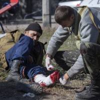 A pro-Russian rebel injured by shrapnel gets a field dressing after action near the airport in Donetsk, eastern Ukraine, on Tuesday. Despite a cease-fire declared a month ago between the Ukrainian forces and pro-Russian rebels, the biggest city in eastern Ukraine remains embroiled in fighting. War fears hang over Ukraine as 12 die despite truce