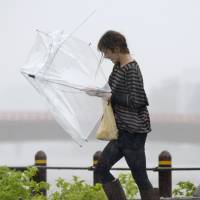 A woman shields herself with a mangled umbrella Monday afternoon as she navigates a road during Typhoon Vongfong in Kochi Prefecture. Typhoon Vongfong sprints toward Tohoku; 61 hurt, one missing