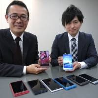 Shigeru Kobayashi (left), general manager of Sharp Corp.'s new business strategic planning department, and Yasuaki Fukuyama, another member of the department, display the electronics maker's latest smartphones on Oct. 28. Sharp develops smartphone feature that speaks for itself