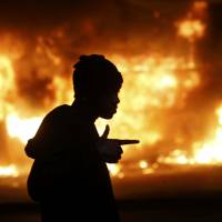A man walks past a burning building in Ferguson, Missouri, early on Tuesday, during rioting that followed a grand jury’s decision not to indict white police office Darren Wilson for the killing of 18-year-old Michael Brown. Anger at Ferguson case split between emotion, evidence