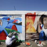 An artist puts finishing touches of a mural depicting various situations when Typhoon Haiyan ravaged Tacloban and other central Philippine provinces last year, on Friday. Various activities were lined up Saturday to commemorate the first anniversary of the massive typhoon that ravaged Leyte, Eastern Samar and other provinces in central Philippines. Year after destructive typhoon, some in Philippines move on, others agonize