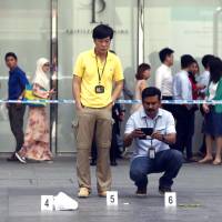 This photo taken Friday by the Straits Times newspaper shows police invetigators working at the crime scene in the Raffles place financial district of Singapore after a man was stabbed, shocking a lunchtime crowd in one of the worlds safest cities. Stabbing in armed robbery stuns lunchtime crowd in Singapore's banking district