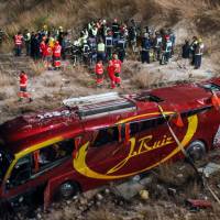 Rescue crews end emergency personel stand near a bus that crashed off the highway near Cieza in the Murcia region, killing 12 people and injuring another 38 on Sunday. Spain's worst coach crash in 13 years claims 14