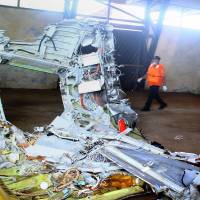 A member of Indonesia's search and rescue team walks past wreckage Monday of AirAsia Flight QZ8501 recovered at sea and stored in a warehouse for investigators in Kumai, Central Kalimantan on Borneo island. Analysts said Wednesday that revelations that the jet climbed at too steep an angle before stalling and plunging into the sea point to striking similarities between the Java Sea accident and the 2009 crash of an Air France jet. AirAsia jet's alarms 'screaming' before crash: investigator