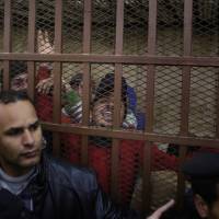 Policemen surround the cell in a courtroom where some of 26 men, who were arrested in a televised raid last month by police looking for gays at a Cairo public bathhouse, celebrate after an Egyptian court acquitted them of debauchery in Cairo on Monday. The trial, which had caused an uproar among activists and rights groups, captured public attention after a pro-government TV network aired scenes of half-naked men being pulled from the bathhouse by police. 26 men acquitted in trial over alleged 'debauchery' in Cairo bathhouse