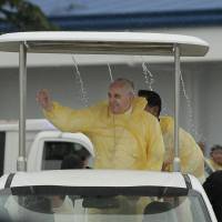 Pope Francis waves to the faithful on his arrival Saturay in Tacloban, Philippines, as rain drips from the roof of his vehicle. For months, Francis has been drafting an encyclical on the environment and global warming that he hopes to release by June or July. In a news conference as he traveled last week to the Philippines, he said global warming was “mostly” man-made. And he said he wanted his encyclical out in plenty of time to be absorbed before the next round of U.N. climate change talks in Paris in November after the last round in Lima, Peru, failed to reach an agreement. Pope's climate-change stand deepens conservatives' distrust